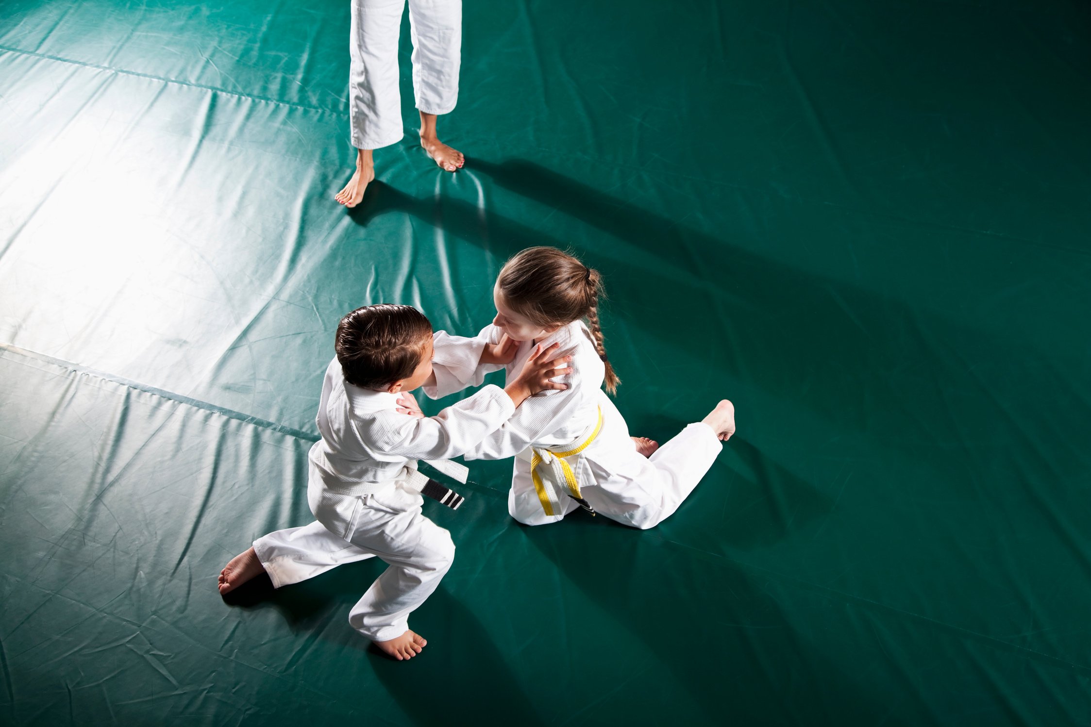 Children practicing Jiu-Jitsu, instructor watching