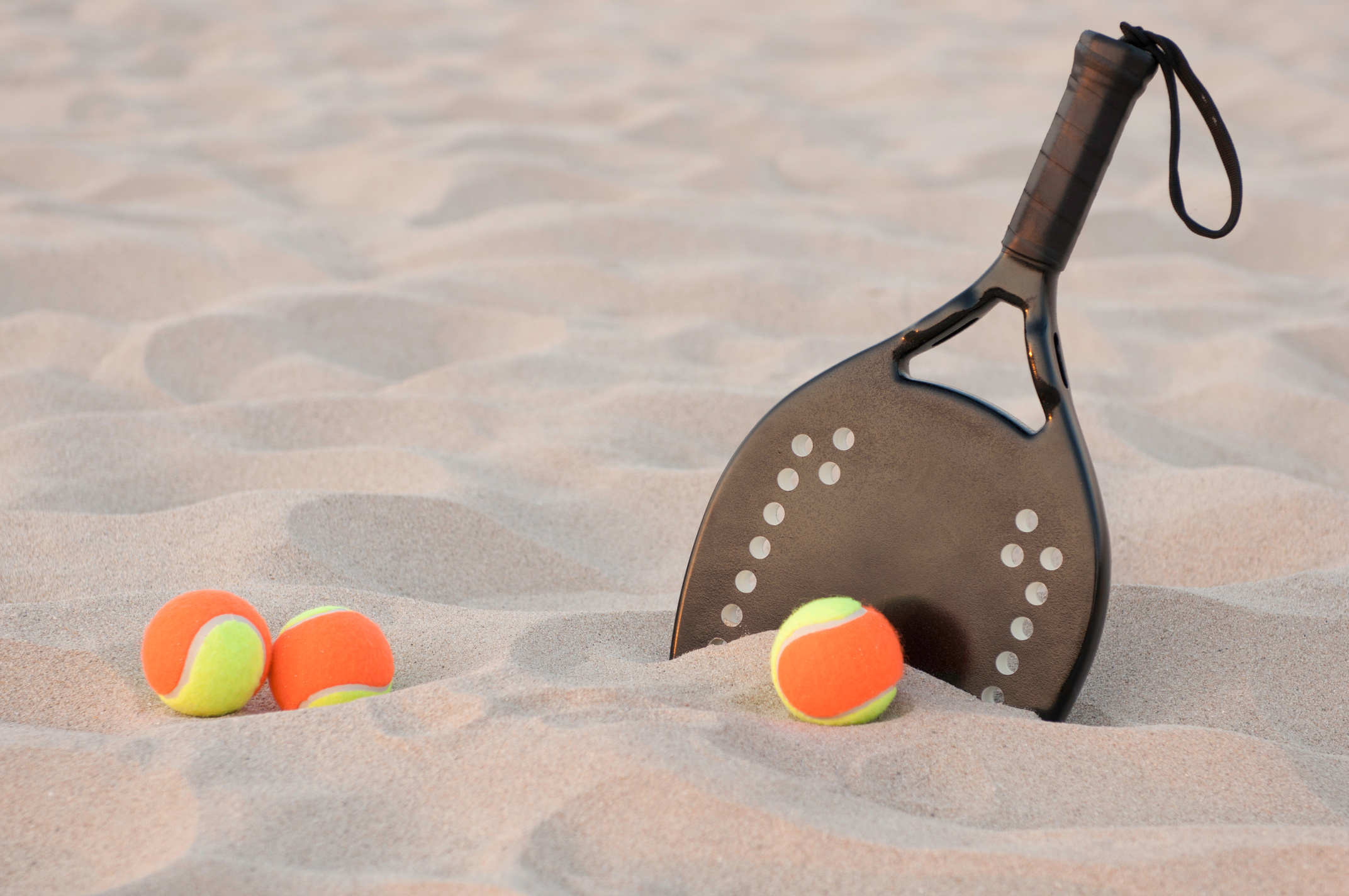 Three beach tennis balls and a racket